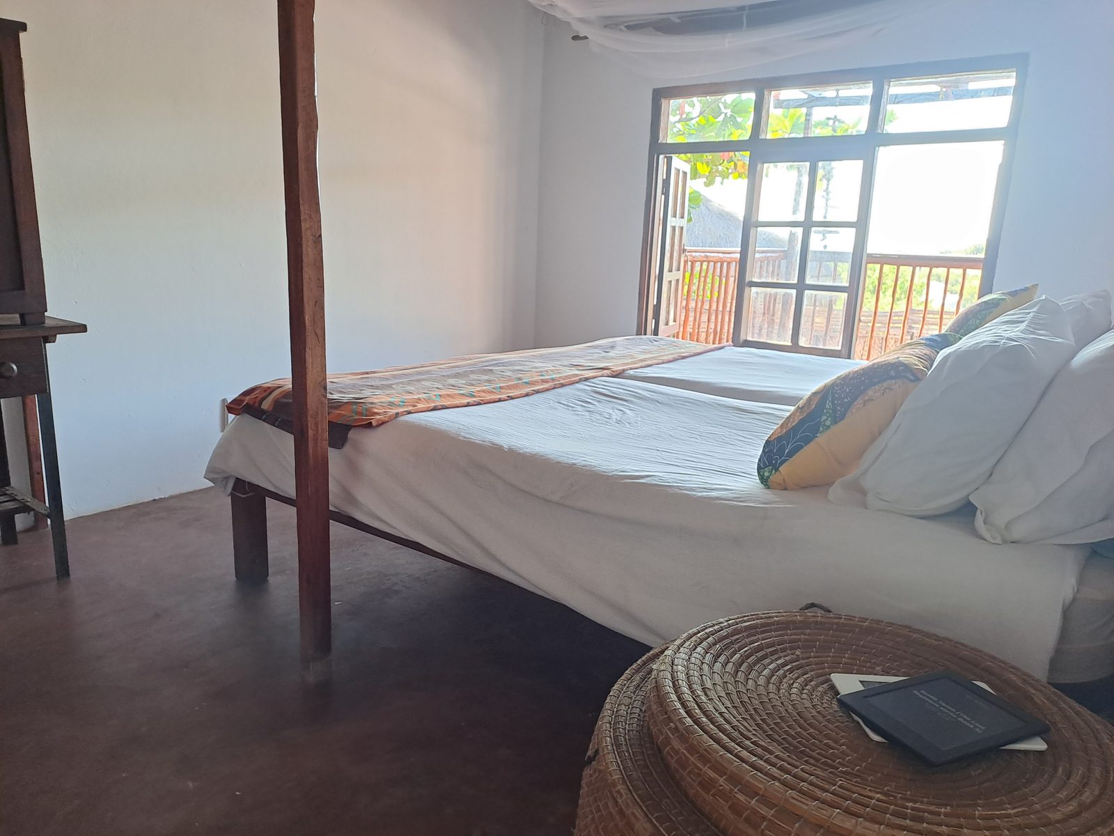 Four-poster bed with mosquito net, doors opening to the deck