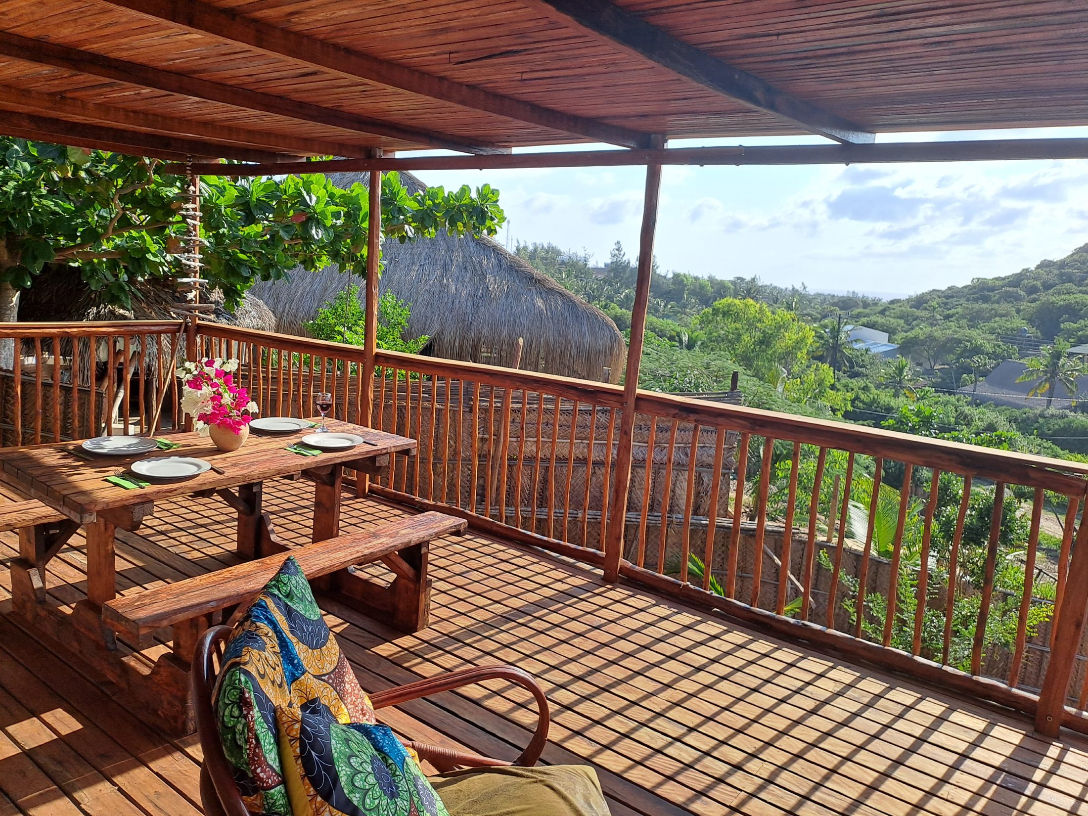 Covered timber deck with dining table overlooking the dunes and ocean at Tofo