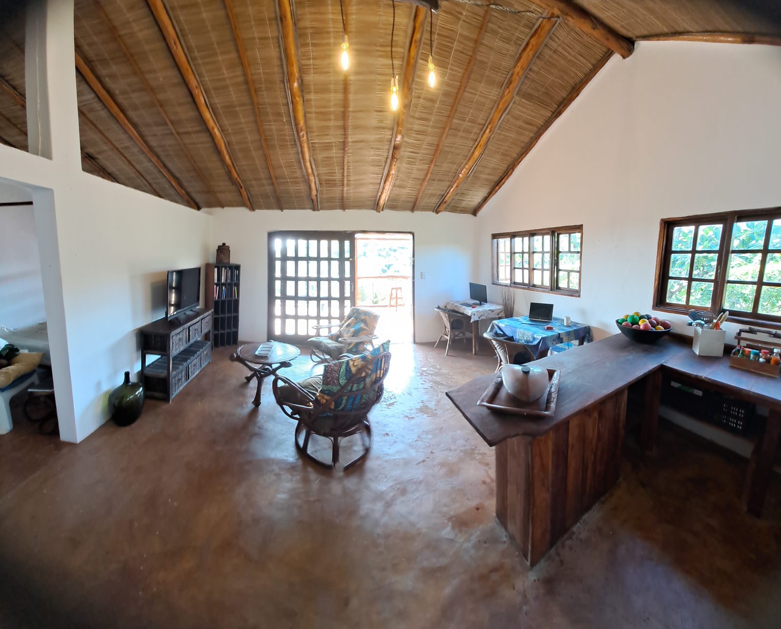 Open-plan living room with cathedral thatch ceiling and timber beams